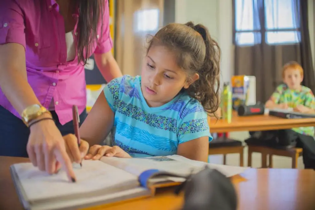 child being helped by a teacher